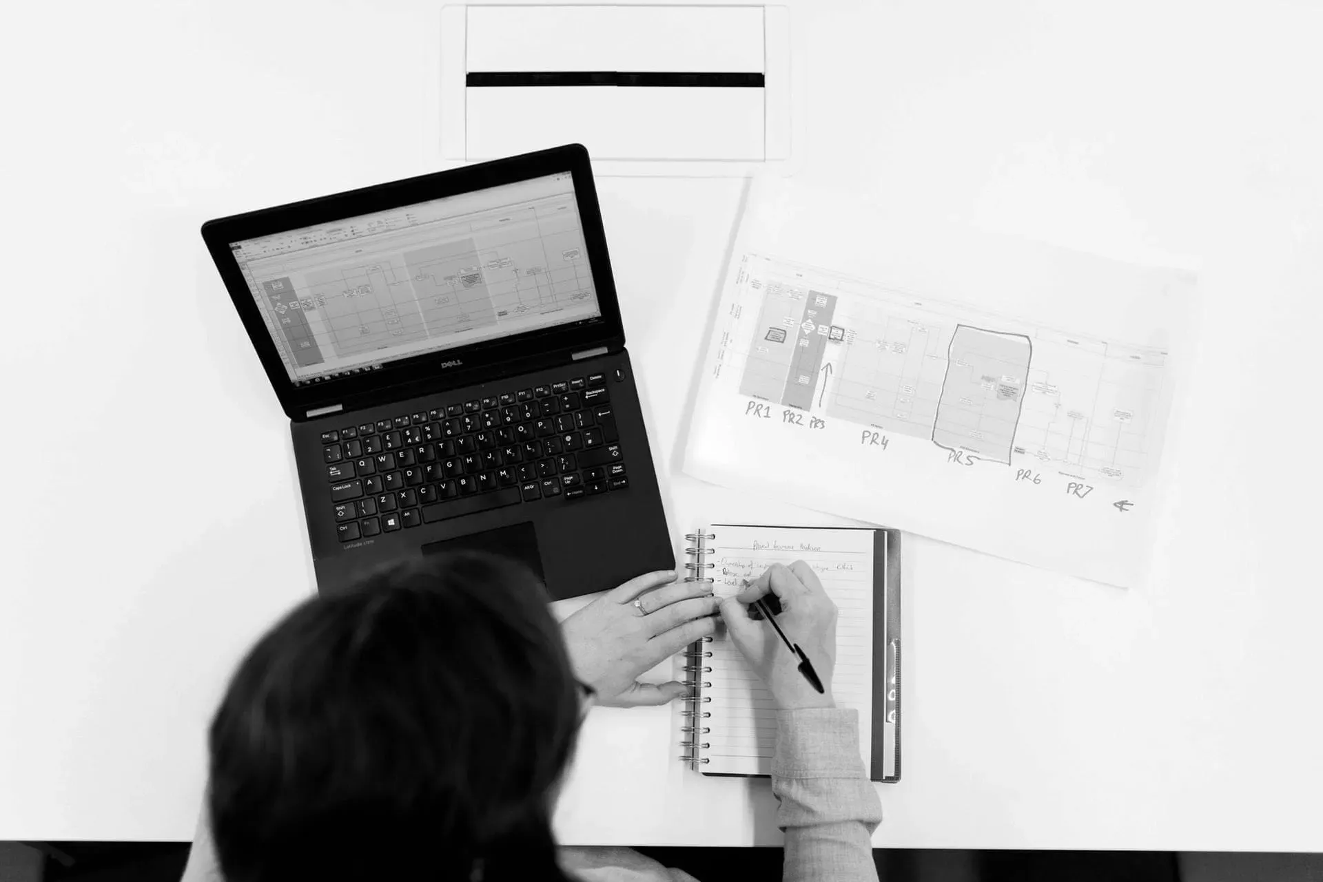 Planung am Laptop mit Grundriss auf dem Schreibtisch